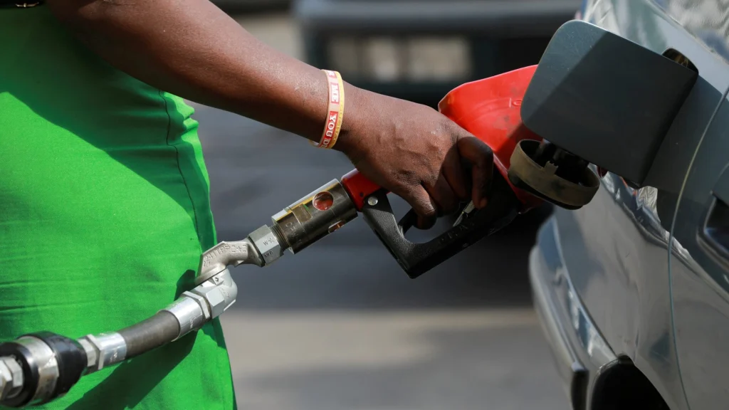 A person fueling a vehicle with a red nozzle at a petrol station in Nigeria, illustrating the positive impact of the news that petrol to sell for N740 per litre.