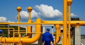 An engineer in blue overalls inspecting industrial gas infrastructure, symbolizing the West African Gas Pipeline: An Economic Survival Strategy for Nigeria and Ghana's Oil and Gas Industry.