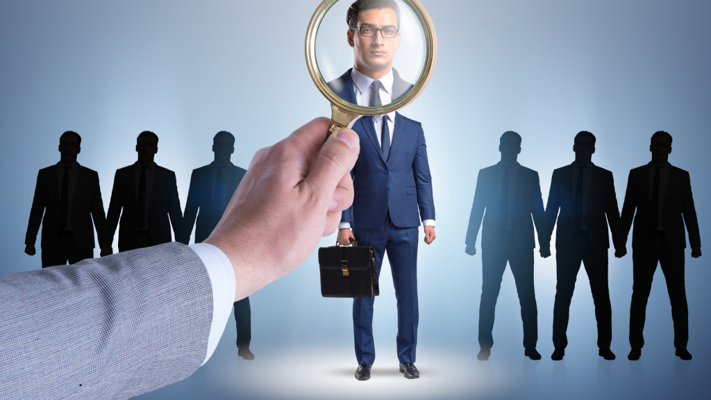 A hand holding a magnifying glass over a candidate's face during a candidate screening process with silhouettes of other applicants in the background.