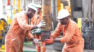 Nigeria upstream oil reforms supporting offshore oil and gas operations with workers handling drilling equipment.