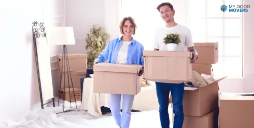 Couple carrying moving boxes into a new home, illustrating work permit vs residence permit vs visa for relocating employees